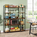Bakers rack against a green wall stocked with crockery, bottles and a microwave
