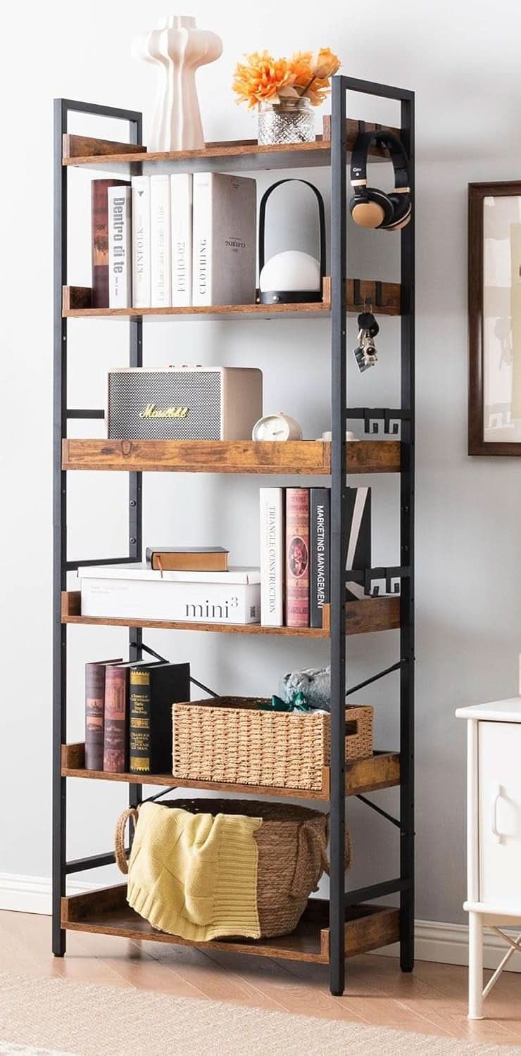 The bookshelf styled with books, a basket and a lamp, with eight S shaped hooks on the upright holding headphones, keys and a bag