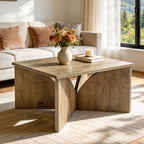 Light oak square coffee table with flowers and a candle on a patterned rug