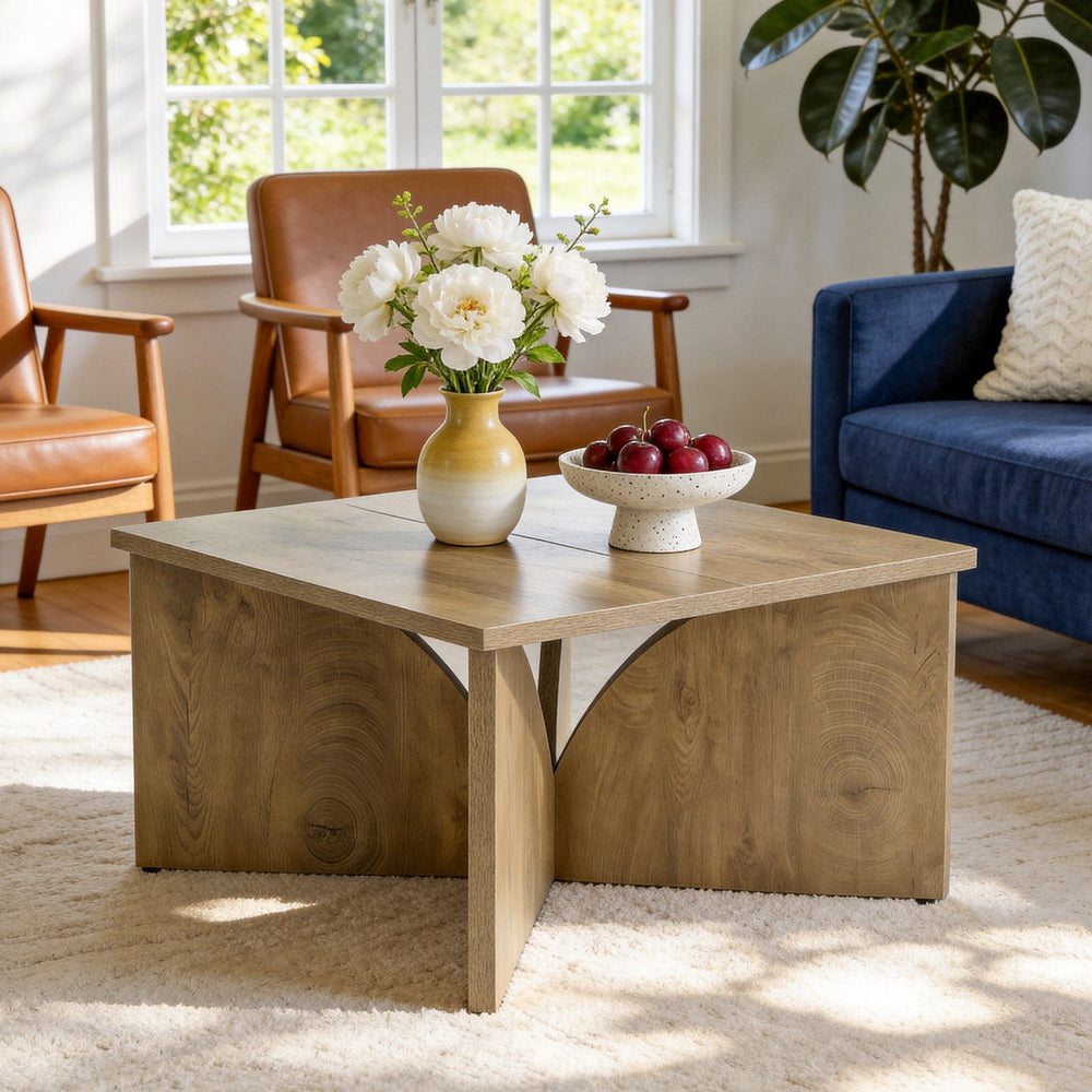 Oak square coffee table with flowers and a fruit bowl between leather chairs and a blue sofa