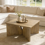 Square table holding a vase and candlesticks beside a white sectional sofa