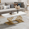 Stowena 47 inch faux marble coffee table with gold geometric base in front of a gray channel sofa