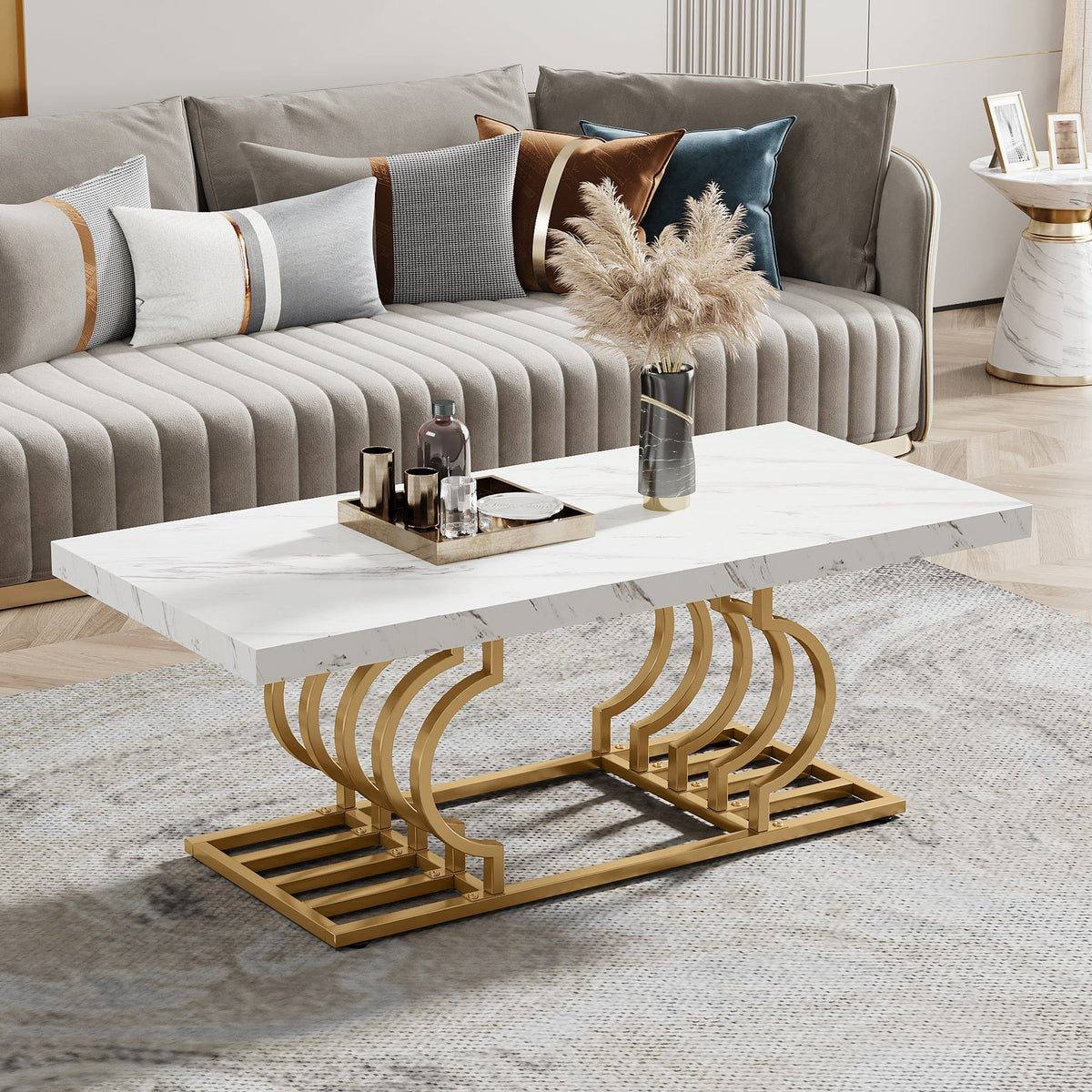 Stowena 47 inch faux marble coffee table with gold geometric base in front of a gray channel sofa