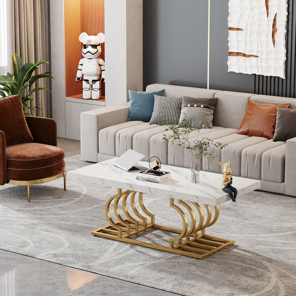 White faux marble table with gold curved base in a modern living room with a green armchair