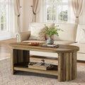 Stowena 47 inch oval coffee table in rich brown holding a tray and books by a cream sofa