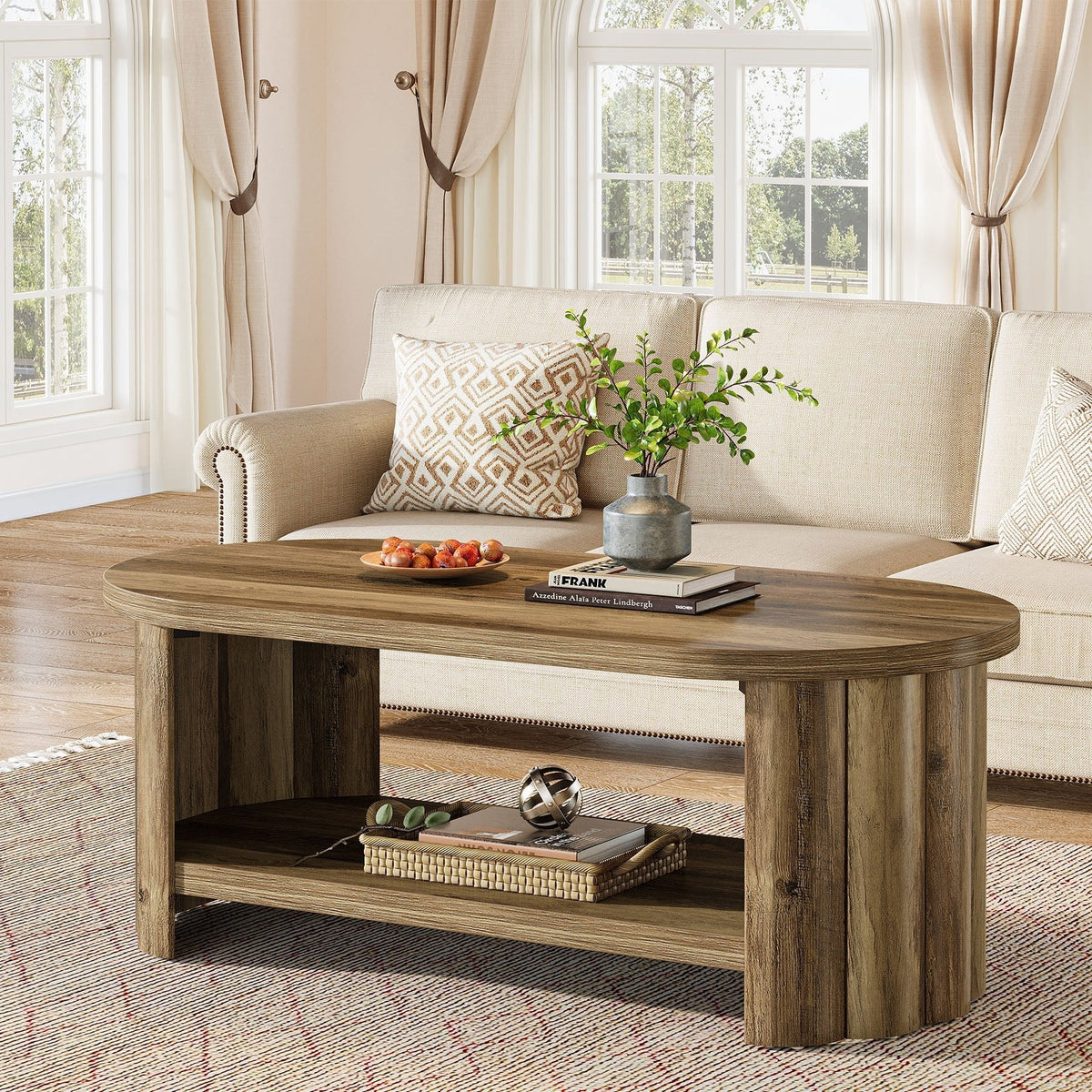 Stowena 47 inch oval coffee table in rich brown holding a tray and books by a cream sofa