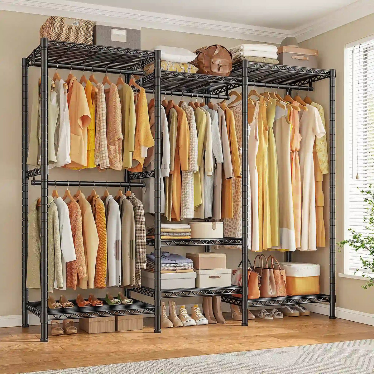 Black freestanding closet rack 69 x 16 x 77 in against a bedroom wall, four hanging sections of shirts and dresses with folded stacks, baskets and shoes on the wire shelves