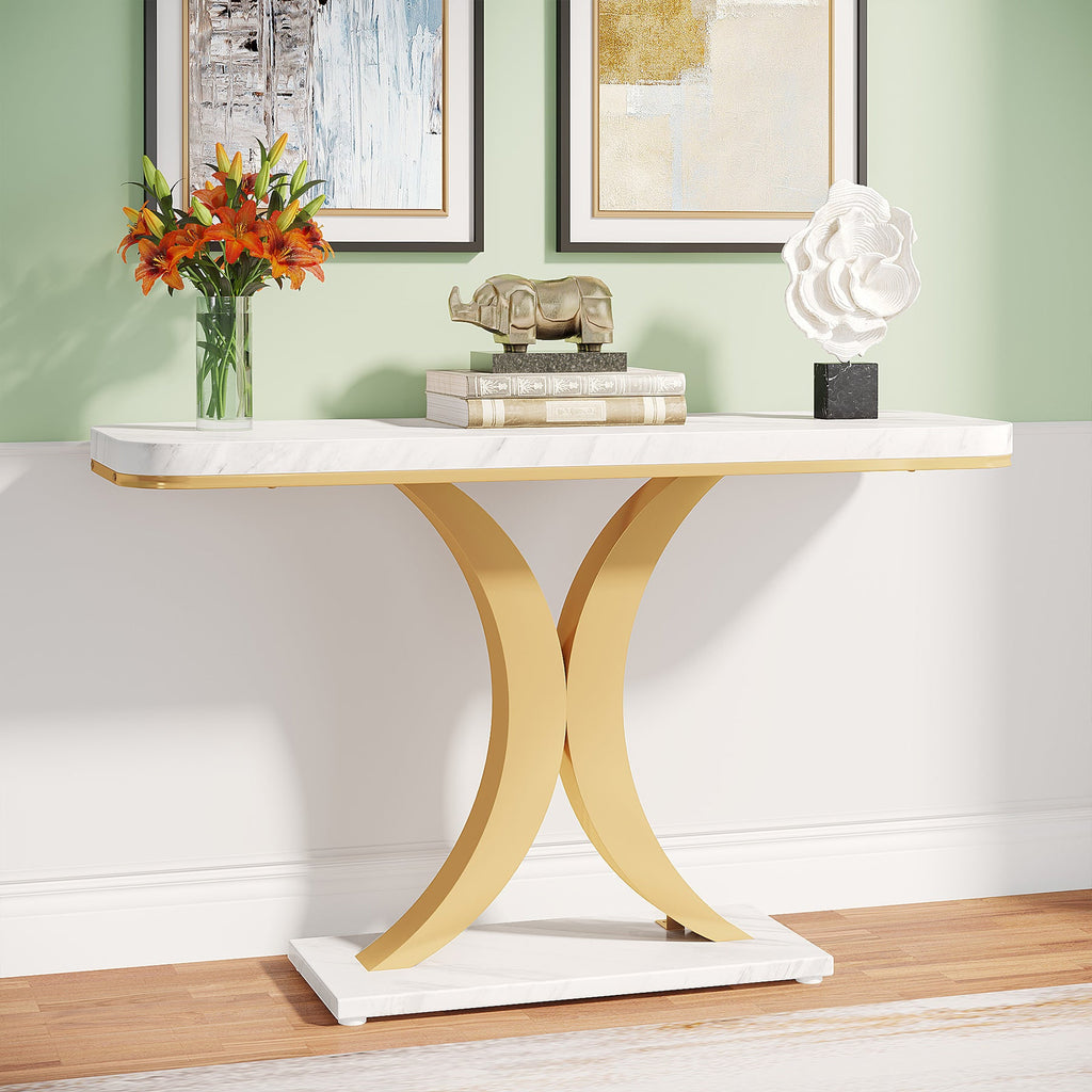 Faux marble console table with a gold double C base against a green wall with flowers and books