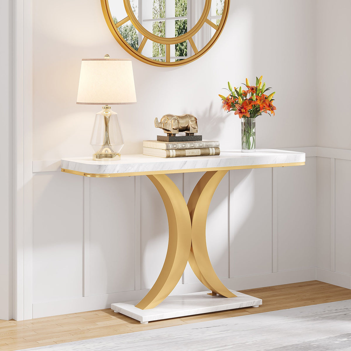 Faux marble console under a round gold mirror with a lamp and flowers on the tabletop