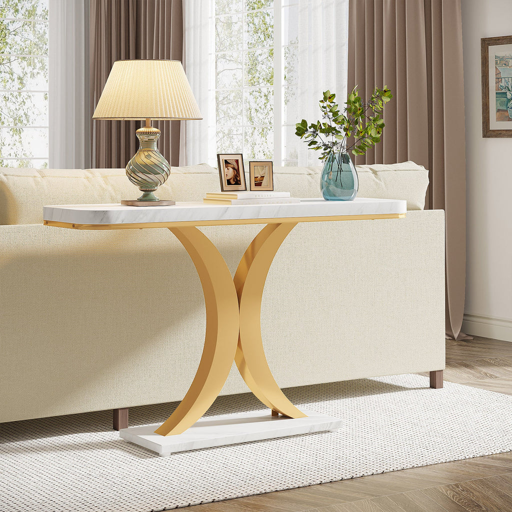 The console table behind a cream sofa holding a lamp and framed photographs