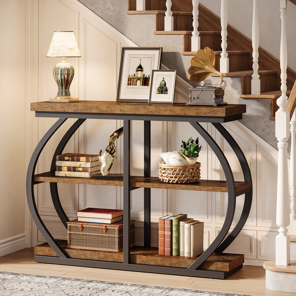 The table under a staircase with framed photographs and a lamp on the tabletop