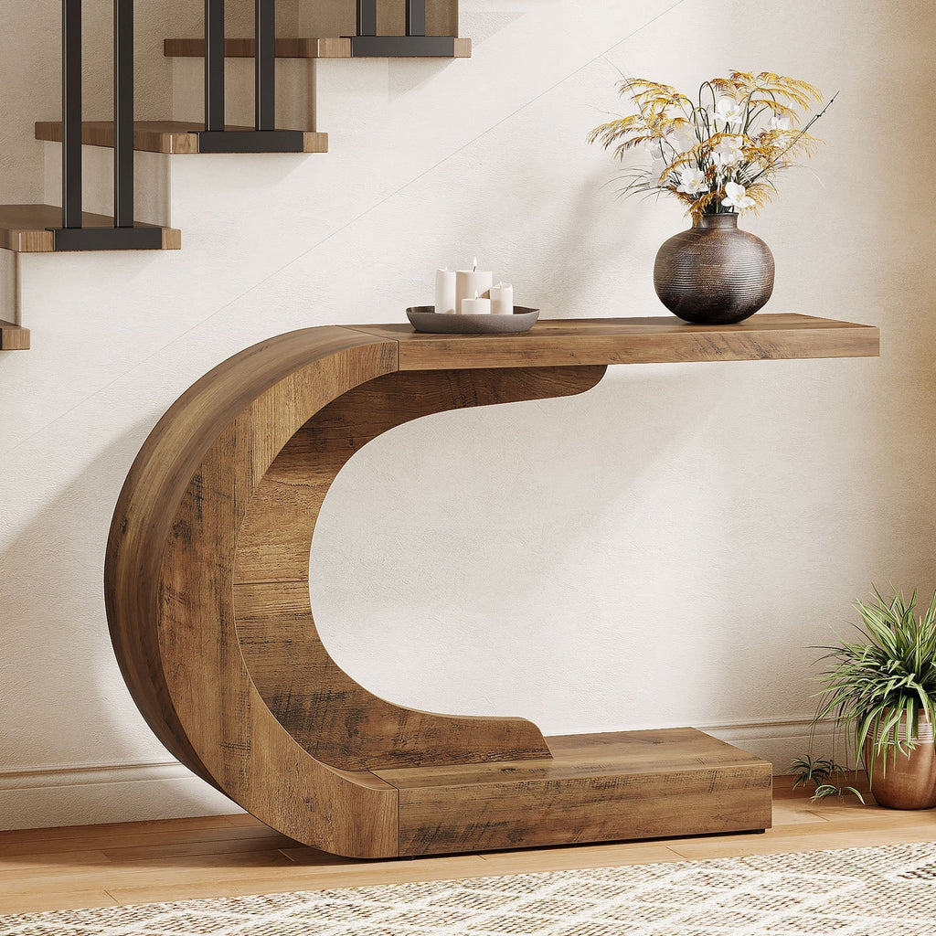 Rustic brown C shaped console table beside a staircase holding a vase and candles