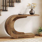 Rustic brown C shaped console table beside a staircase holding a vase and candles