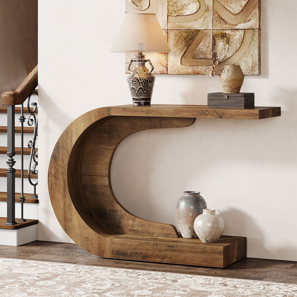 The C shaped console against a wall with pottery on the tabletop and a book on the lower arm