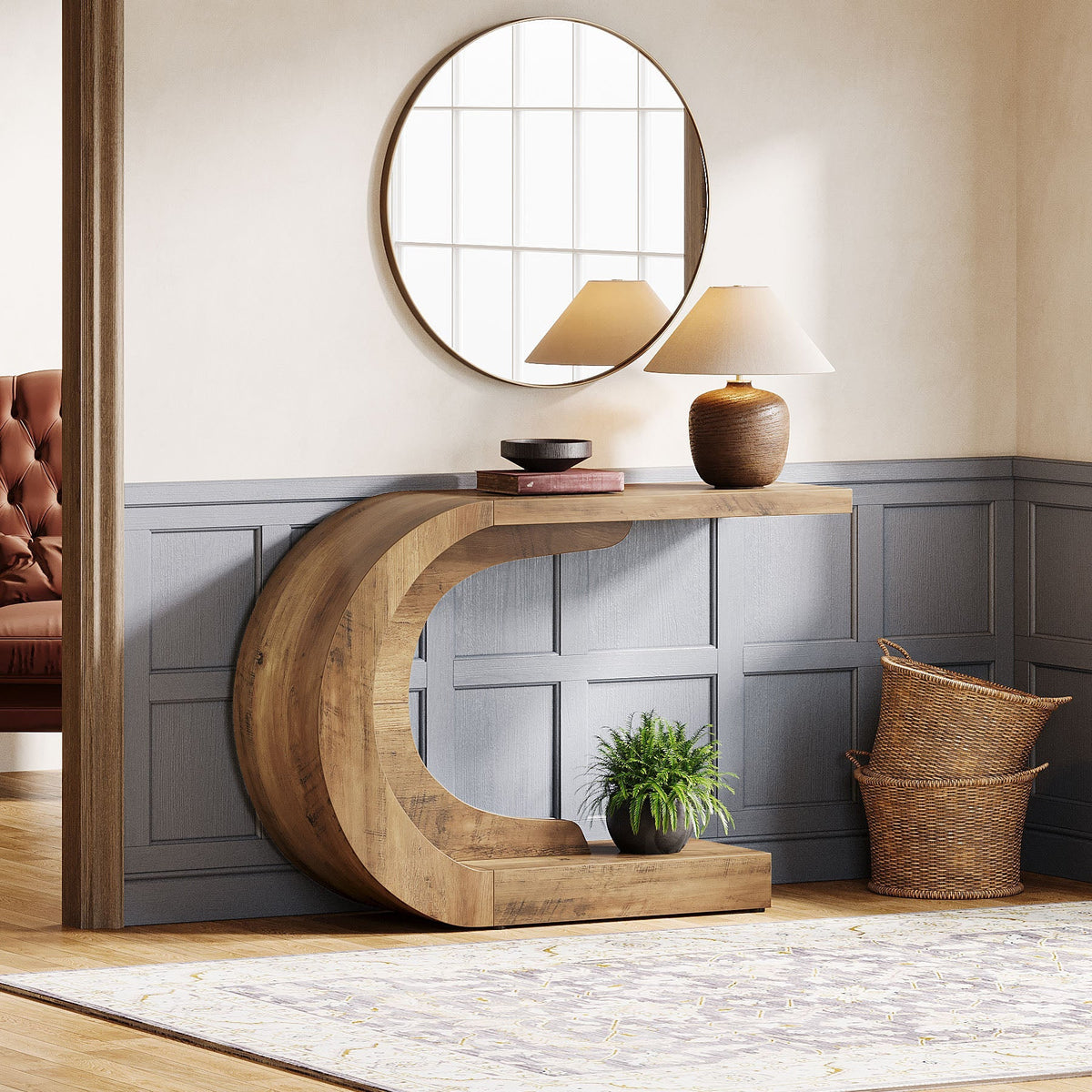 The curved console in a hallway with a round mirror and baskets beside it
