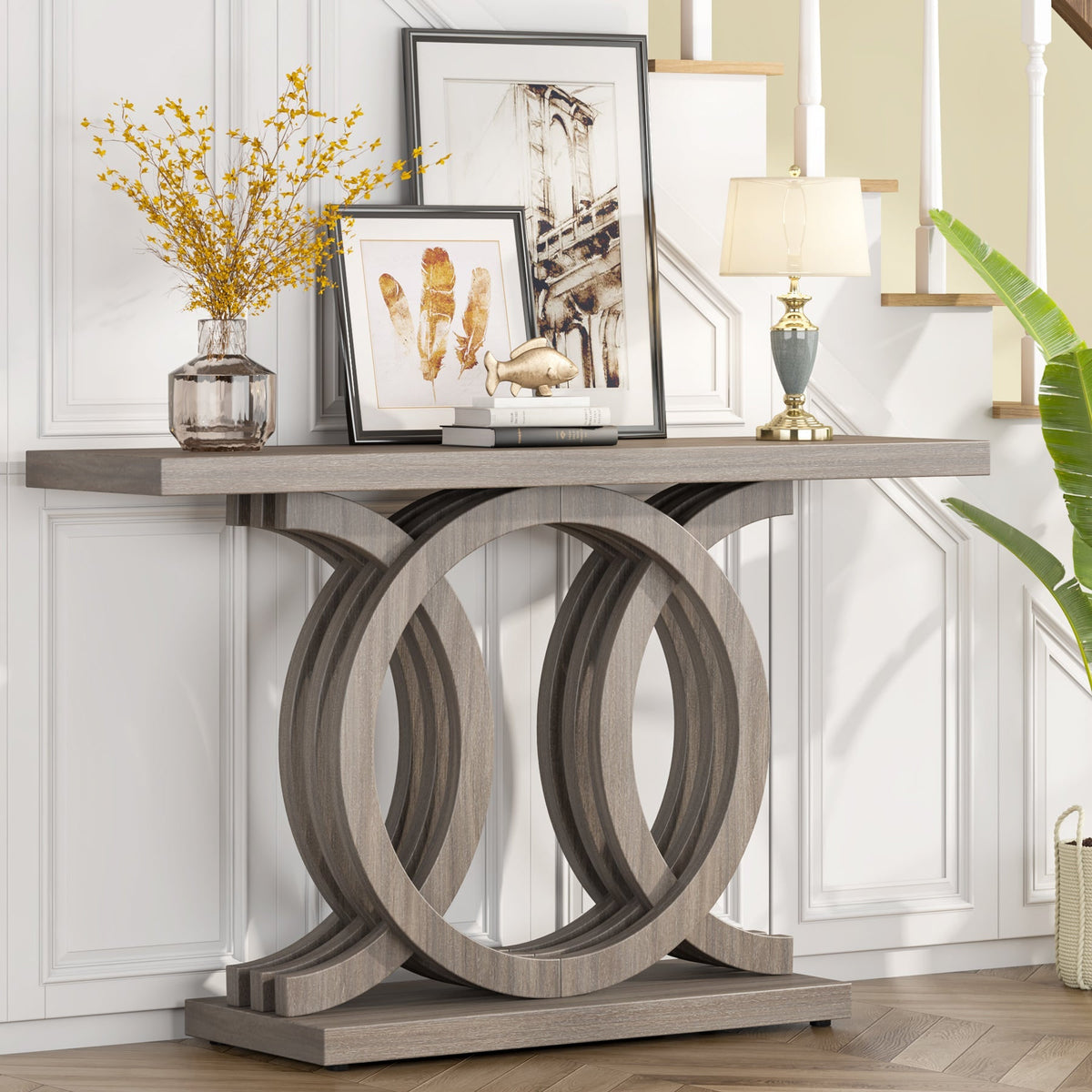 Gray 55 inch console table with an interlocking ring base under framed art, holding a lamp