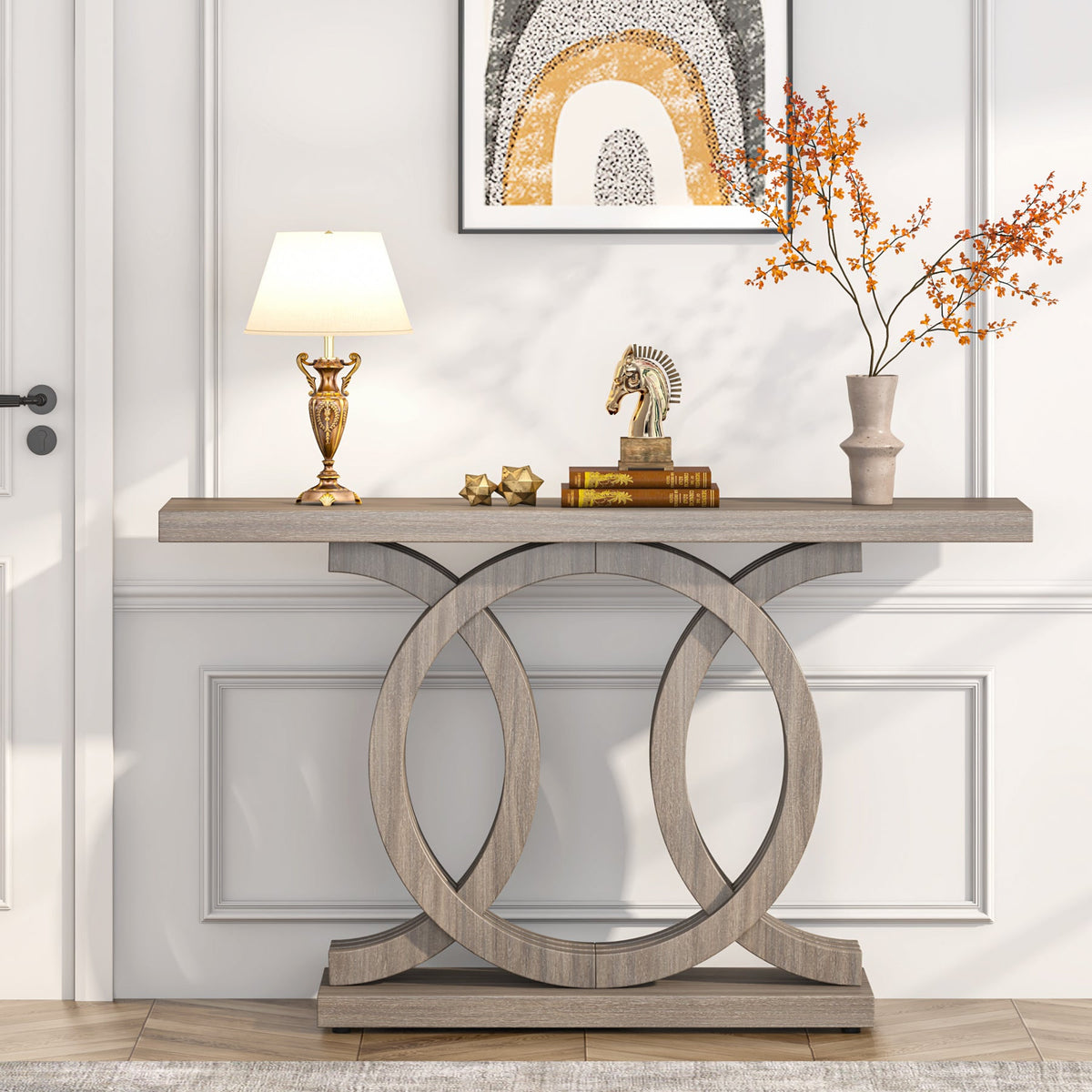 The long console against a panelled wall with a lamp, books and an ornament on top