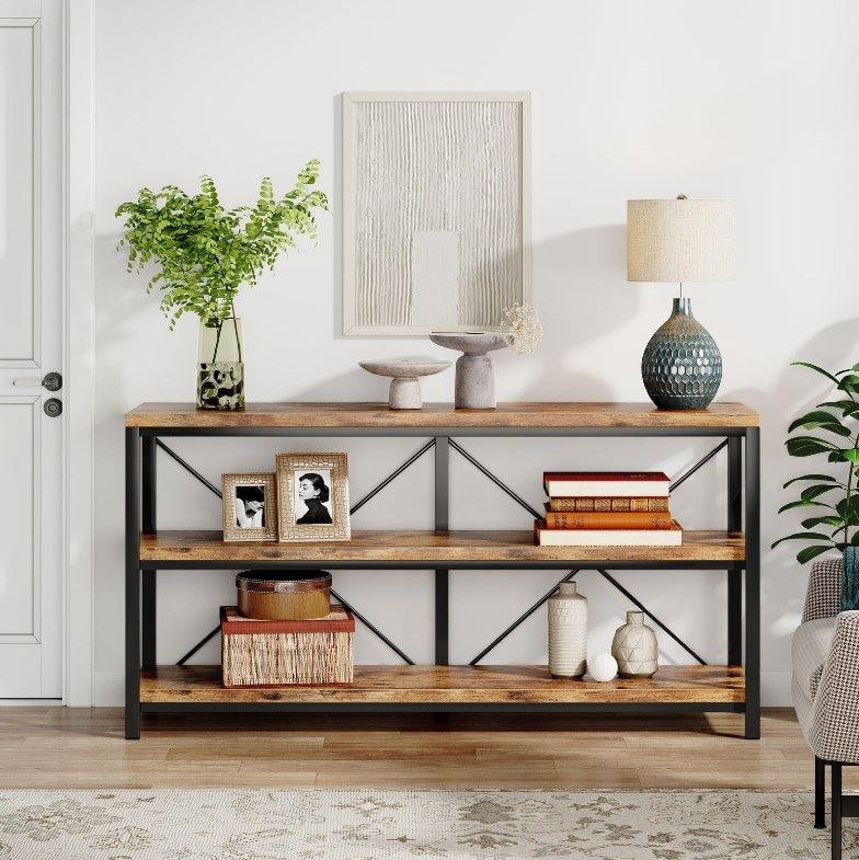 Rustic 55 inch three tier console table along a wall with books, frames and baskets on its shelves