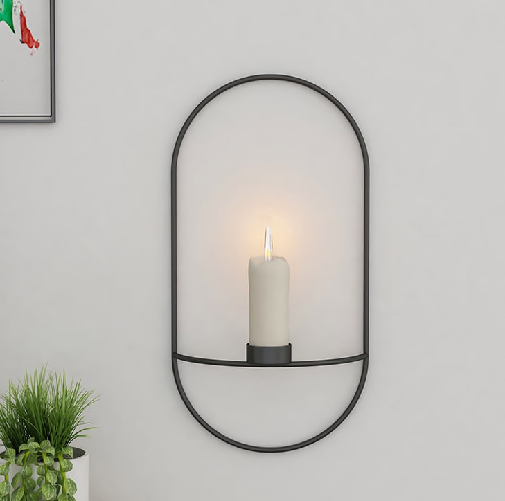 Black wall candle sconce holding a lit candle, view 2