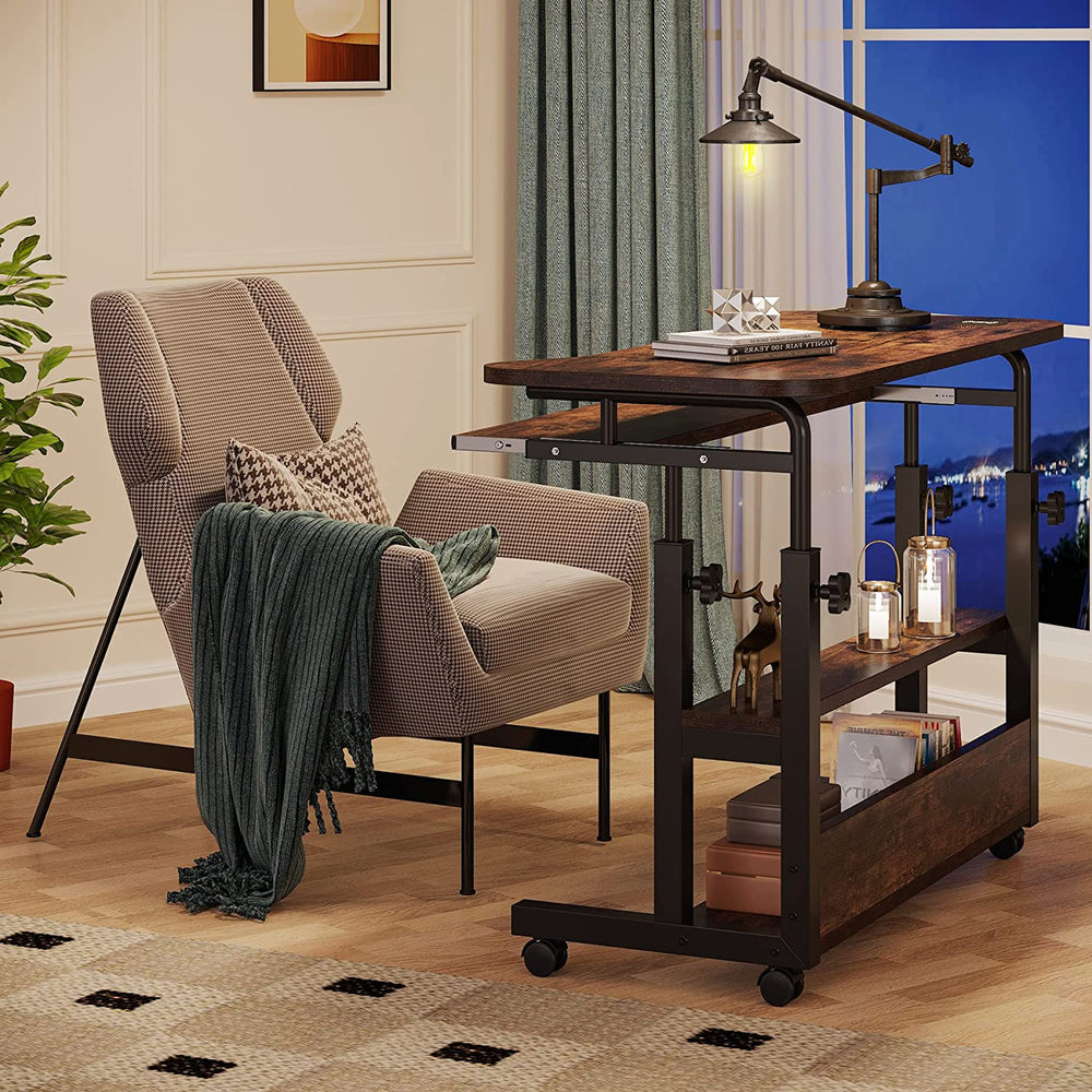 Mobile desk rolled beside an armchair holding a lamp and books on the lower shelves
