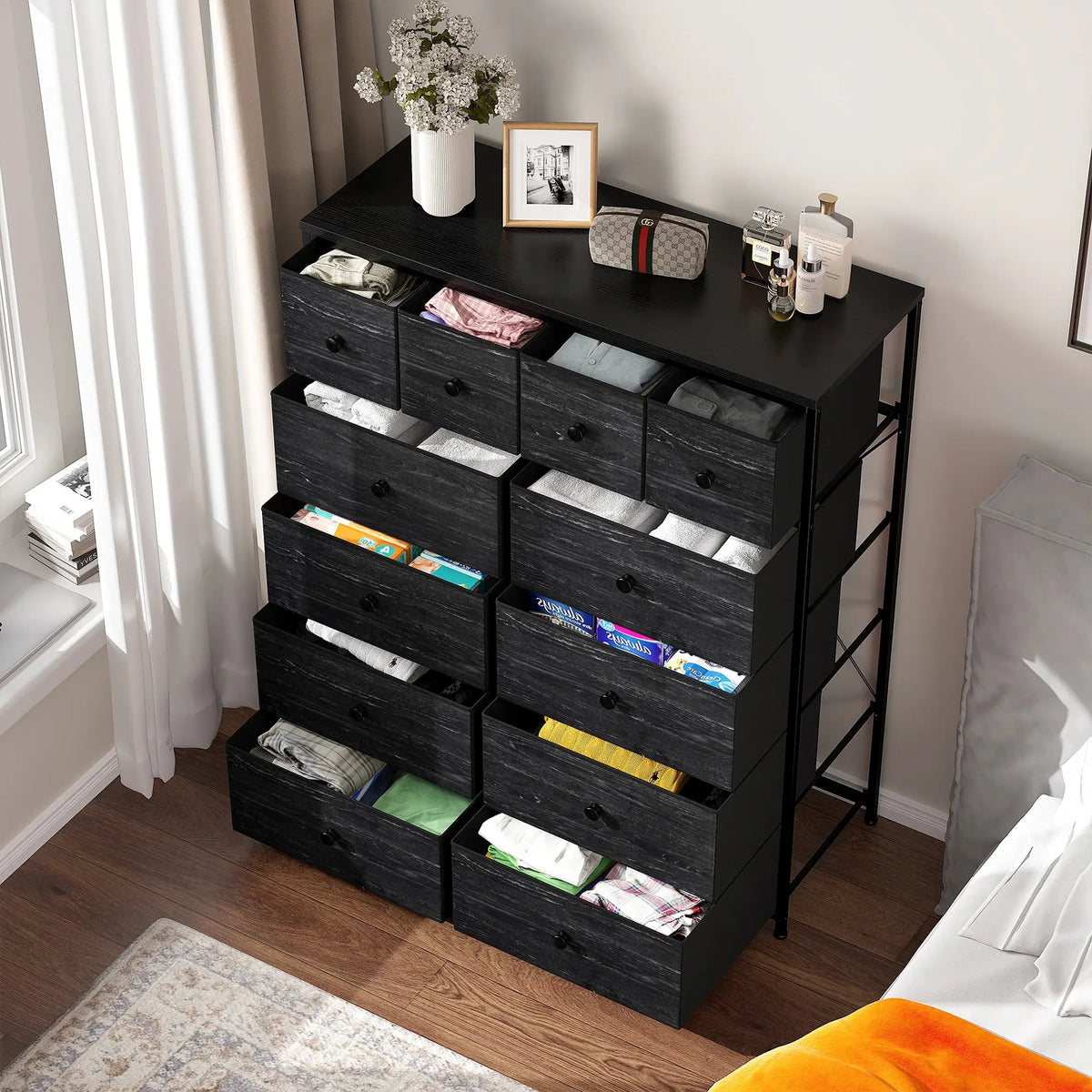 The dresser with several drawers open showing folded clothes in each
