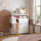 The white dresser in a bedroom with books and boxes in the open compartments above the drawers