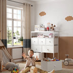 White fabric dresser against a wall with folded towels and boxes on the open shelves