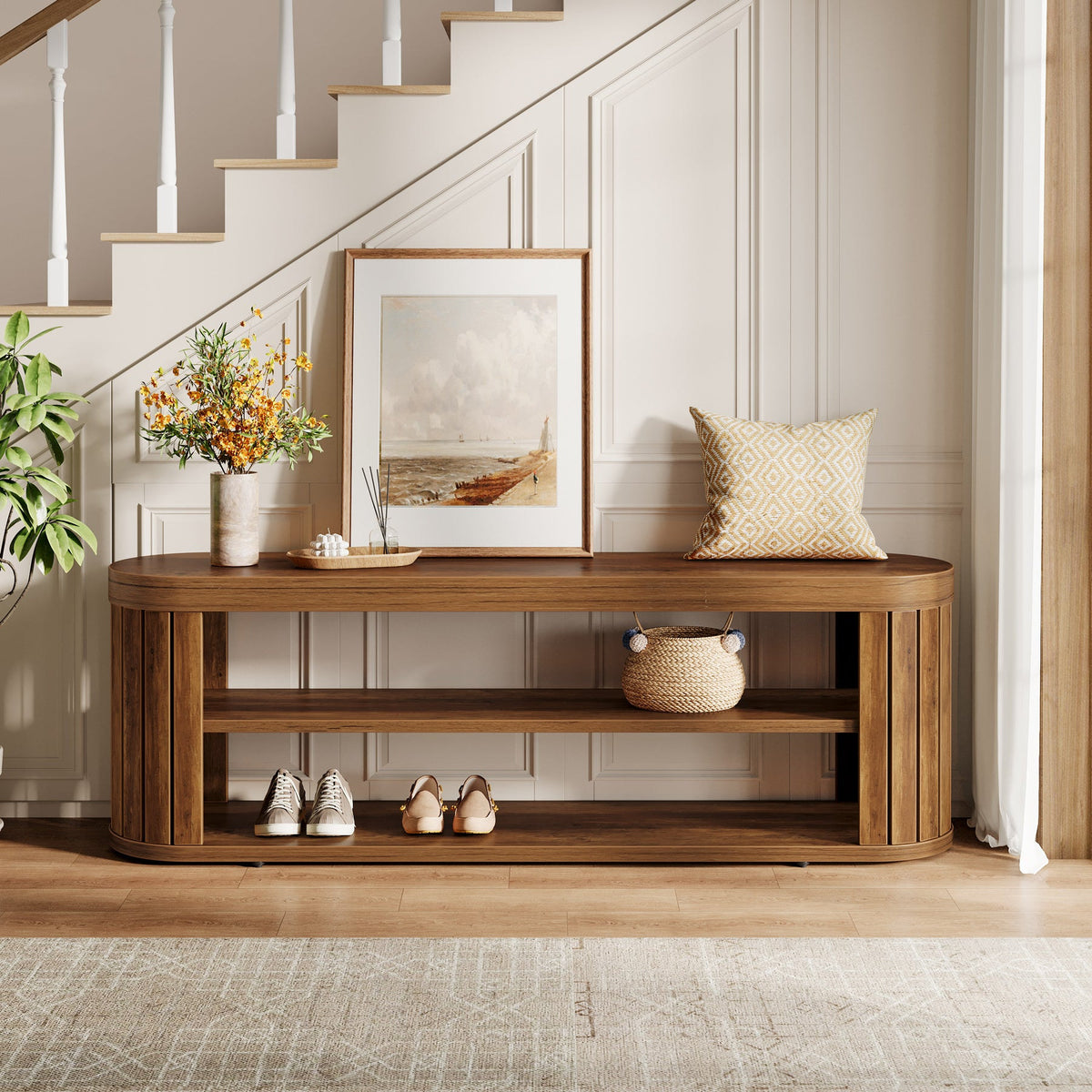 Entryway bench under a staircase with art and a vase on top