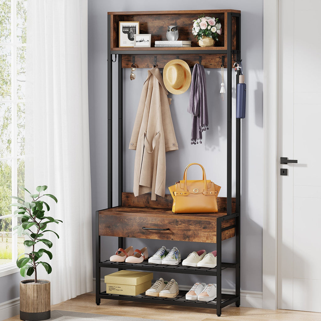 Stowena hall tree with shoe bench, drawer and hooks holding coats by a white door