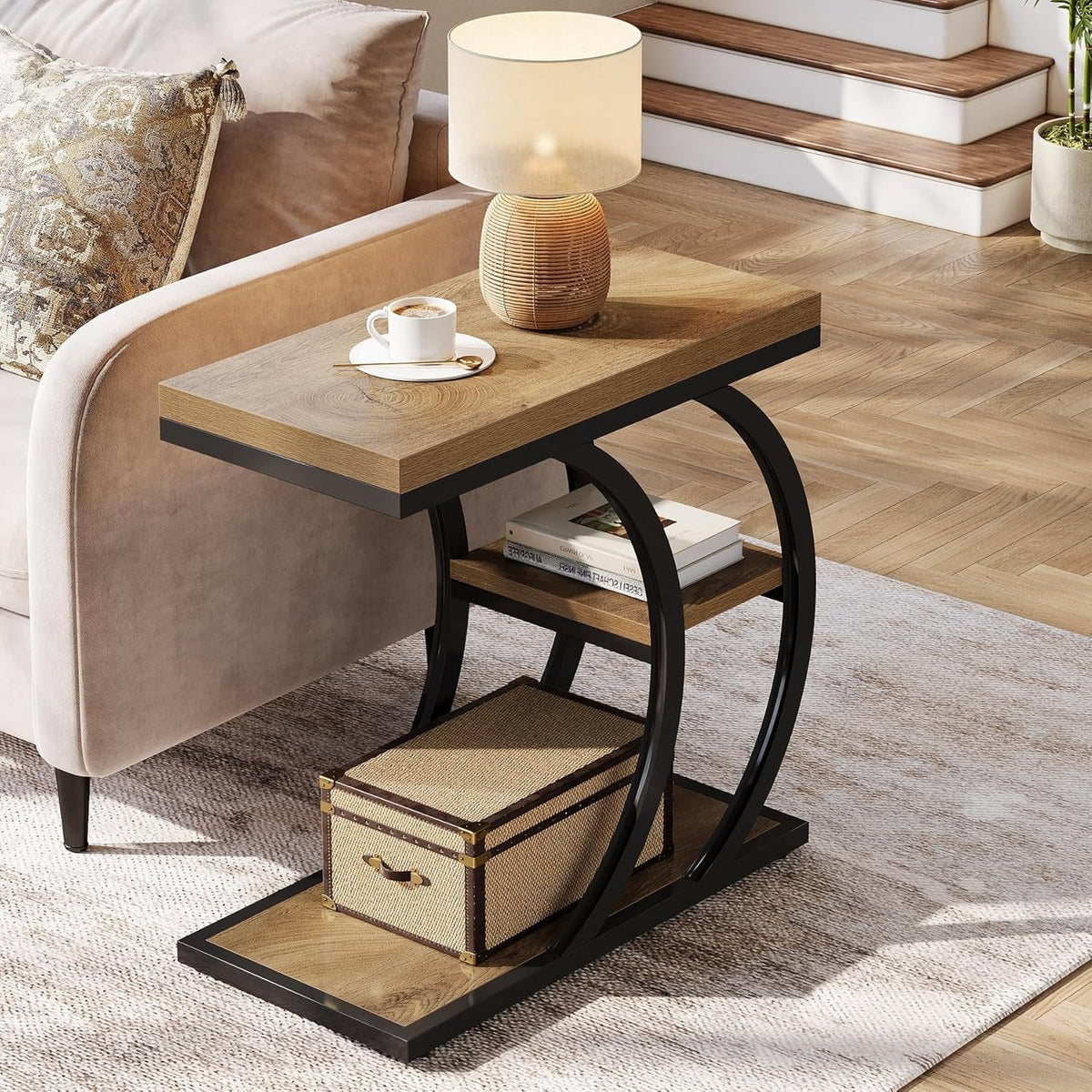 C shaped side table beside a sofa holding a mug and a lamp