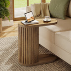 Stowena fluted C shaped end table with an oval top beside a sofa