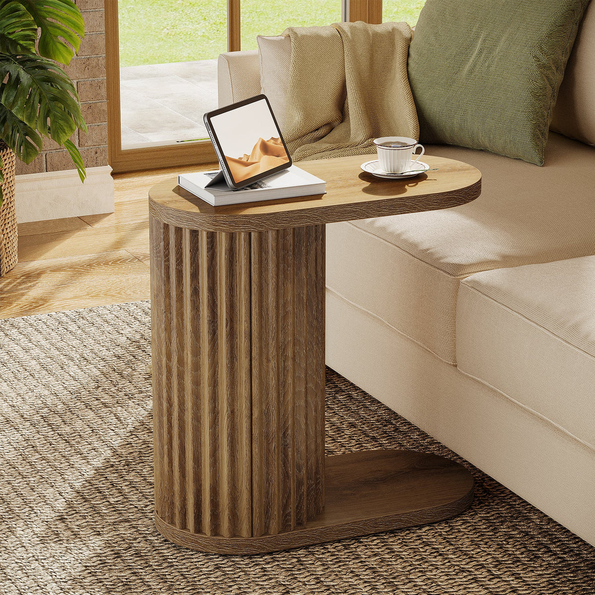 Stowena fluted C shaped end table with an oval top beside a sofa
