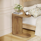 Fluted side table beside a bed holding flowers and a clock