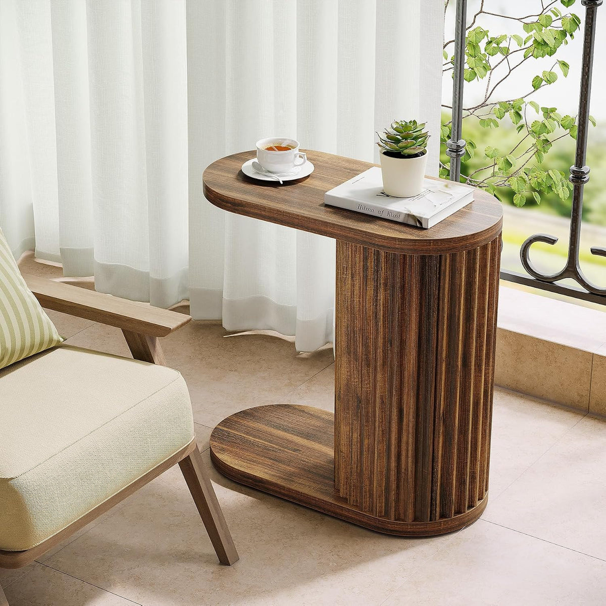 Fluted oval table beside an armchair with a cup and a plant