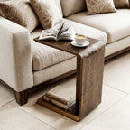 C shaped end table holding an open book and coffee beside a beige couch