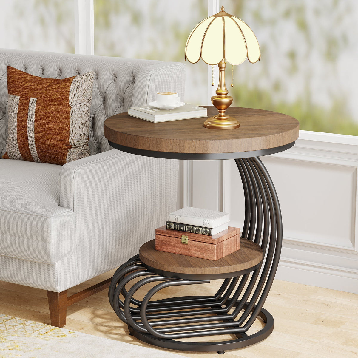 Round end table beside an armchair holding a lamp and books