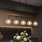 Five light chandelier with clear crackle glass globes lit above a dark kitchen counter