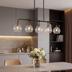 The chandelier lit over a dining table in a grey and wood kitchen