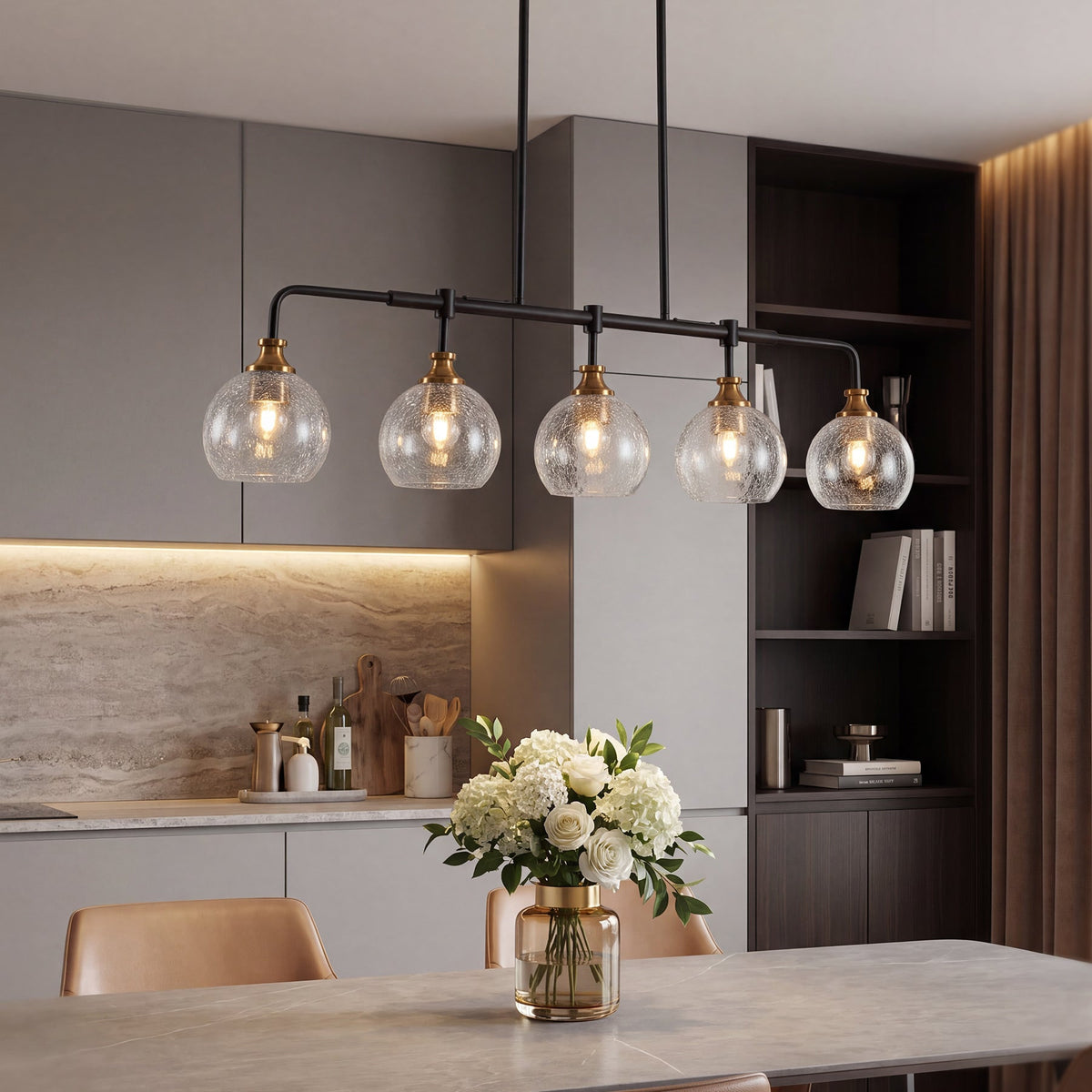 The chandelier lit over a dining table in a grey and wood kitchen