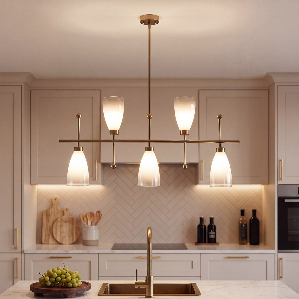 The brass chandelier lit above a kitchen island with a herringbone tiled wall behind
