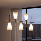 Close view of the brushed brass bar and gradient shades beside a glazed wall at dusk