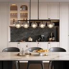 The chandelier lit above a marble island in a cream and black kitchen