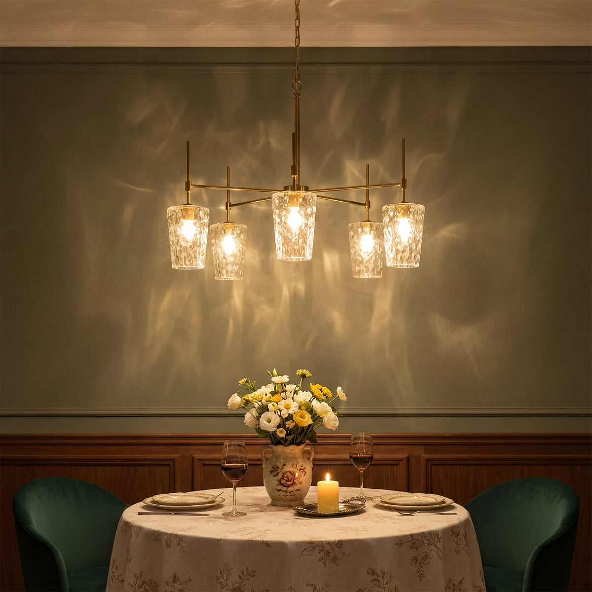The chandelier casting a soft water pattern shimmer on a green dining room wall