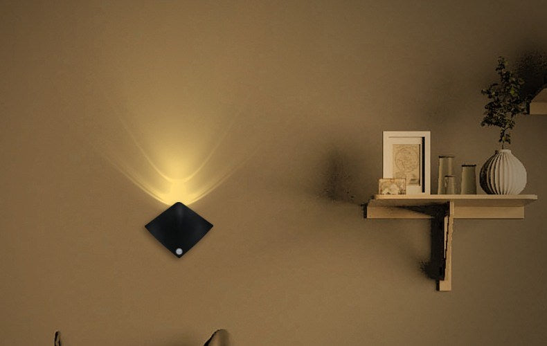 Black sensor wall lamp glowing warm next to a wood wall shelf