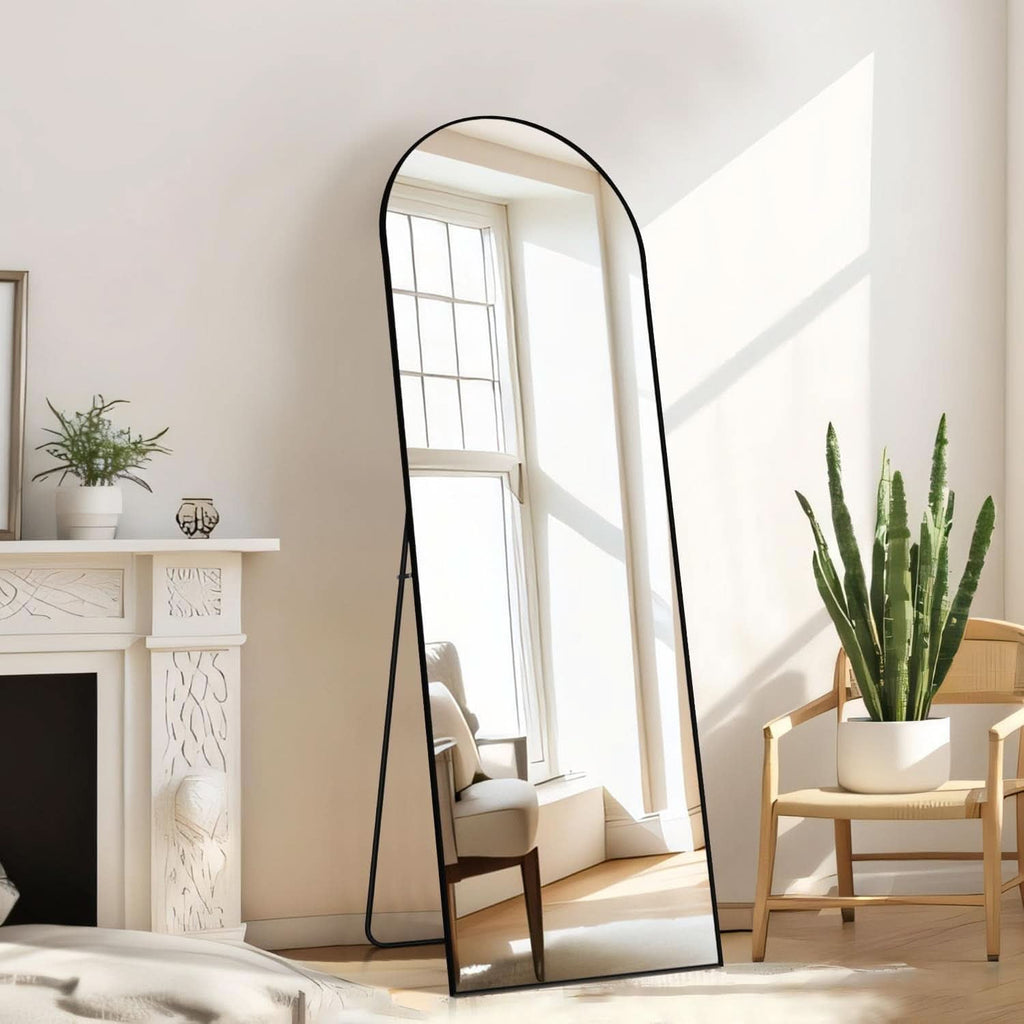 Stowena black arched full length mirror standing in a living room by a window