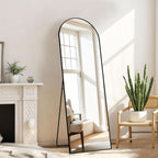Stowena black arched full length mirror standing in a living room by a window