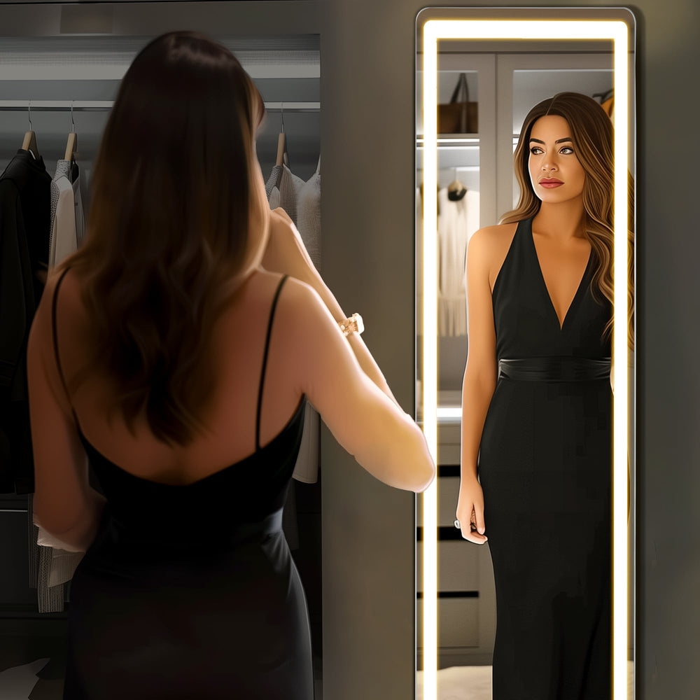 Woman in a black dress checking her outfit in the lit rounded-corner full length mirror