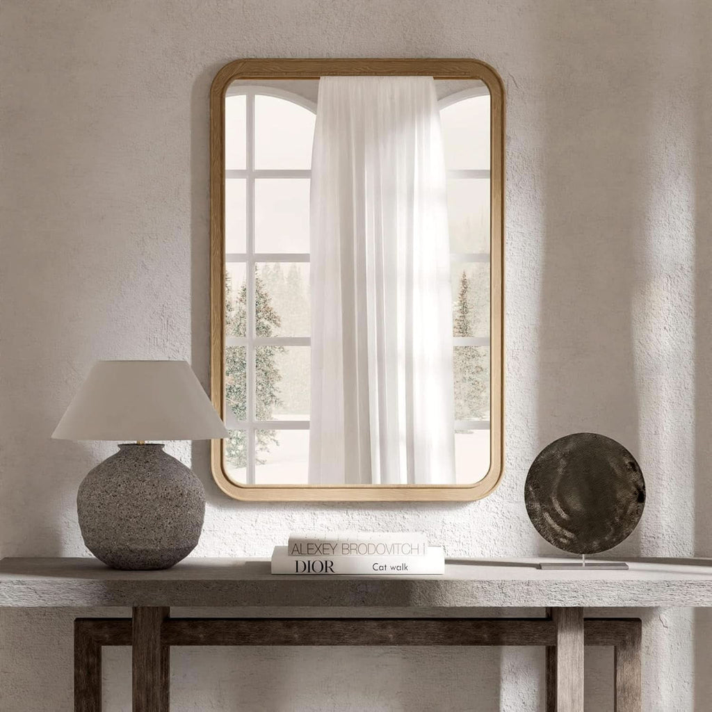 Natural pine framed mirror above a console table beside a lamp