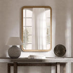 Natural pine framed mirror above a console table beside a lamp