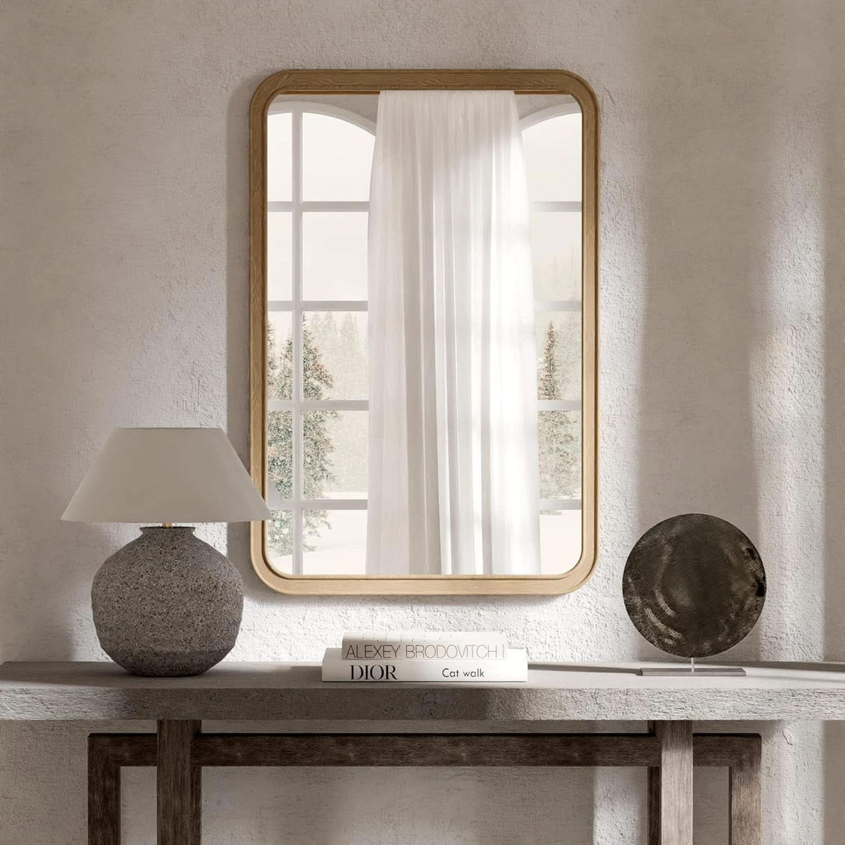Natural pine framed mirror above a console table beside a lamp
